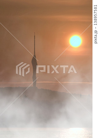 Ethereal Sunrise over Camlica Tower in Fog. A cinematic view of Istanbul's Camlica Tower silhouetted against a glowing sun and dense mist during a dramatic sunrise. Ethereal Sunrise over Camlica Tower in Fog. A cinematic view of Istanbul's Camlica Tower silhouetted against a glowing sun and dense mist during a dramatic sunrise. 138957581