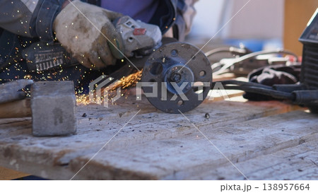 Closeup Construction Worker Grinding Flange, Sparks Fly Against Scaffold Backdrop, Heavy Gloves And Safety Gear, Outdoor Repair On Platform With Concrete And Timber Nearby Closeup Construction Worker Grinding Flange, Sparks Fly Against Scaffold Backdrop, Heavy Gloves And Safety Gear, Outdoor Repair On Platform With Concrete And Timber Nearby 138957664