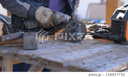 Closeup Hands Cutting Metal With Angle Grinder, Protective Gloves Sending Sparks Across Wooden Workbench Circular Disc Shaving Steel, Power Tool Vibration, Gritty Workshop Atmosphere, 138957710