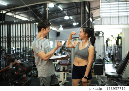 A personal trainer is discussing and reviewing physical progress with his female client. 138957711