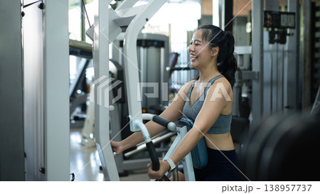 Athletic woman exercising back muscles on seated Row Machine in gym Athletic woman exercising back muscles on seated Row Machine in gym 138957737