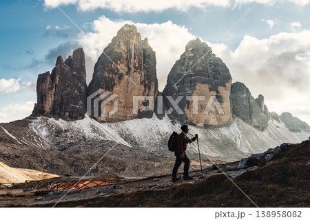 Male hiker stands on trail admiring the massive Tre Cime mountain and blue sky in Dolomites, Italy Male hiker stands on trail admiring the massive Tre Cime mountain and blue sky in Dolomites, Italy 138958082