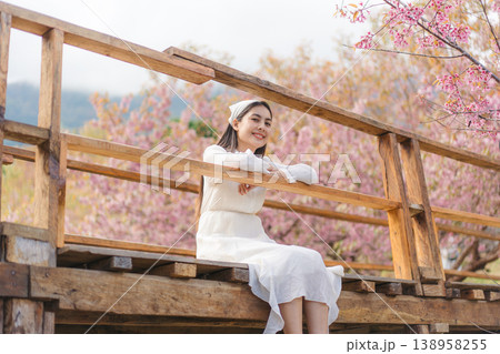 Relaxed woman sitting on wooden bridge during Wild Himalayan Cherry blooming in Khun Wang, Chiang Mai Relaxed woman sitting on wooden bridge during Wild Himalayan Cherry blooming in Khun Wang, Chiang Mai 138958255