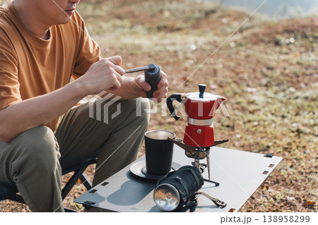 Man making espresso coffee with moka pot and coffee maker while camping mountain Man making espresso coffee with moka pot and coffee maker while camping mountain 138958299