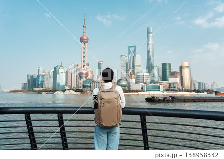 Backpacker looking at Oriental Pearl Tower and iconic skyscraper from The Bund viewpoint Backpacker looking at Oriental Pearl Tower and iconic skyscraper from The Bund viewpoint 138958332