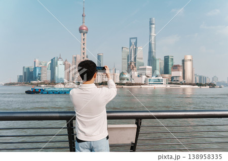 Male tourist taking a photo with smartphone at Oriental Pearl Tower and Shanghai skyscraper 138958335