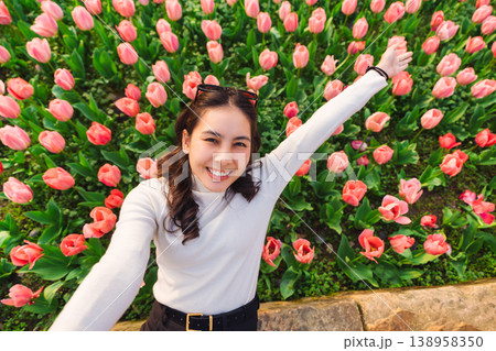 Beautiful female enjoying on colorful tulip flower blooming in botanical garden Beautiful female enjoying on colorful tulip flower blooming in botanical garden 138958350