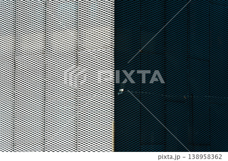 Abstract geometric modern perforated metal mesh facade featuring high contrast and security camera 138958362