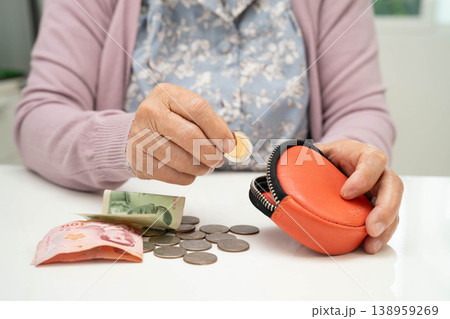 Asian senior or elderly old lady woman holding counting coin money in bag. Poverty, saving problem in retirement. 138959269