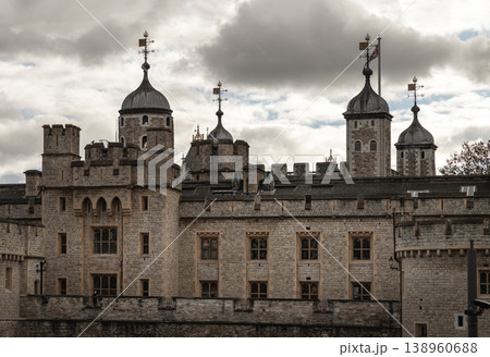 Beneath a brooding, silver-edged sky, the Tower of London stands as a formidable sentinel of history. Its rugged limestone walls, weathered by centuries of salt and secrets, rise with a heavy, ancient 138960688