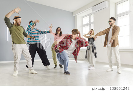 Modern indoor dance studio class, diverse group of dancing young people actively following trainer Modern indoor dance studio class, diverse group of dancing young people actively following trainer 138961242