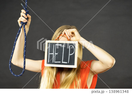 Suicidal woman holding help sign next to rope Suicidal woman holding help sign next to rope 138961348