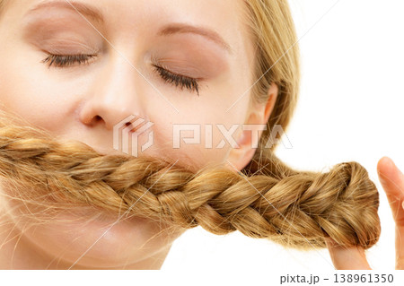 Blonde girl covering her mouth with braid hair Blonde girl covering her mouth with braid hair 138961350