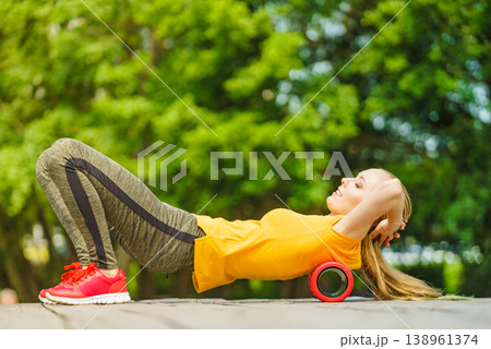 Girl doing exercises outdoor, using roller Girl doing exercises outdoor, using roller 138961374