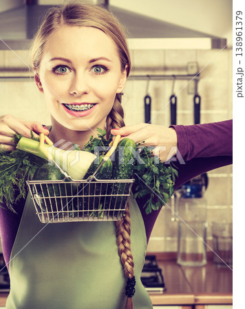 Woman in kitchen having vegetables holding shopping basket Woman in kitchen having vegetables holding shopping basket 138961379