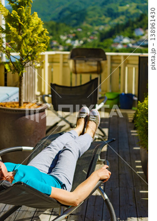 Woman relaxing in chair on veranda. 138961430