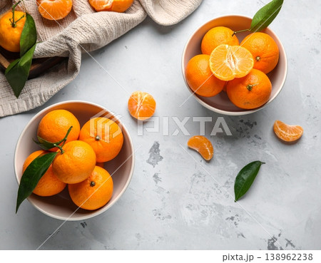 Bowls with sweet mandarins on grey background Bowls with sweet mandarins on grey background 138962238