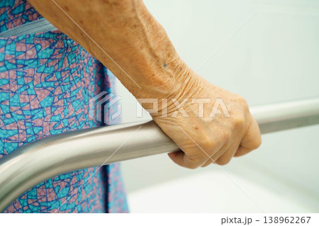 Asian elderly woman patient use toilet support rail in bathroom. 138962267