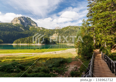 Calm lake with forest reflection under blue sky Calm lake with forest reflection under blue sky 138962712