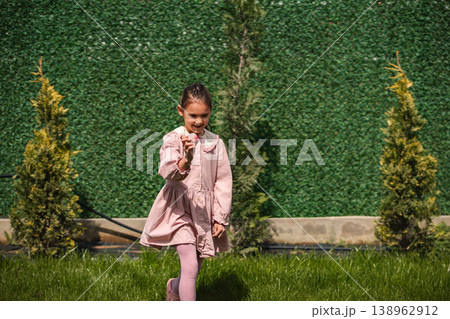 Little girl playing with a small object outdoors Little girl playing with a small object outdoors 138962912