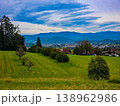 Panoramic view of a small town in a lush green valley at the foot of blue mountains. 138962986