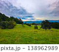 Panoramic view of a small town in a lush green valley at the foot of blue mountains. 138962989