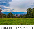 Panoramic view of a small town in a lush green valley at the foot of blue mountains. 138962991