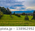Panoramic view of a small town in a lush green valley at the foot of blue mountains. 138962992