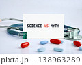 A white card with the words SCIENCE VS MYTH written on it lies with a stethoscope and scattered red and blue pills 138963289