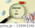 A magnifying glass focuses on Doctor versus DIY text, placed on a light surface with assorted blue and orange capsules and a medicine blister pack 138963296