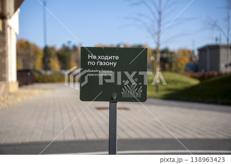 Green warning sign asking not to walk on the grass, placed in a landscaped urban area with blurred background. Green warning sign asking not to walk on the grass, placed in a landscaped urban area with blurred background. 138963423