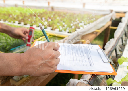 Smart agriculture technology concept - Farmer taking note water ph value of organic hydroponic plant nursery farm. Smart agriculture technology. 138963639