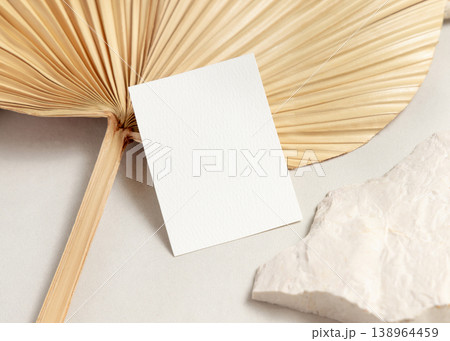 Blank card mockup with dried palm leaf on beige stone top view, boho wedding stationery Blank card mockup with dried palm leaf on beige stone top view, boho wedding stationery 138964459