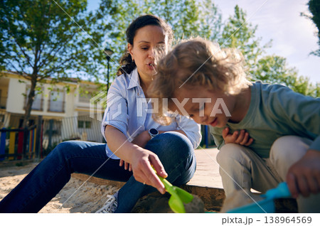 Mother And Toddler Playing Together In A Sandbox At A Sunny Urban Park 138964569
