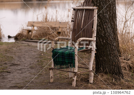 Rustic Birch Wood Chair with Green Plaid Blanket by a Calm Lake in Autumn Landscape 138964762