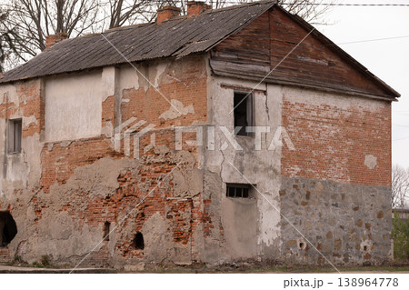 Old Abandoned Brick Building with Peeling Plaster and Corrugated Roof in Rustic Style 138964778