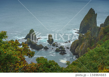 Muroran, Hokkaido, Japan - Oct 04 2024, panoramic aerial view of the picturesque Pacific ocean coast with sharp cliffs and high mountain slopes, in a storm, it's raining, at daytime, Muroran, Japan Muroran, Hokkaido, Japan - Oct 04 2024, panoramic aerial view of the picturesque Pacific ocean coast with sharp cliffs and high mountain slopes, in a storm, it's raining, at daytime, Muroran, Japan 138964883