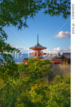 Kyoto, Japan - Oct 11 2024, vertical view through foliage of Kiyomizu-Dera temple complex with a pagoda, without people, with a clear blue sky and a forest in foreground, at daytime, Kyoto, Japan 138964895