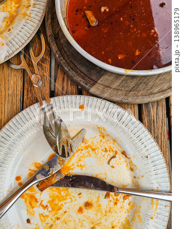 Top View of Dirty Plates with Red Sauce and Cutlery on Wooden Table After Meal 138965179