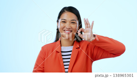 Perfect sign, portrait and business woman in a studio for approval and satisfaction hand gesture. Happy, smile and professional young Asian creative designer with ok emoji isolated by blue background 138965301