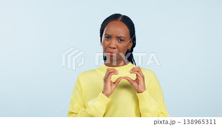 Woman, portrait and hands of broken heart in studio for sad breakup, depression and lonely emotion on blue background. Unhappy african model show heartbreak emoji for divorce, trauma and pain of love Woman, portrait and hands of broken heart in studio for sad breakup, depression and lonely emotion on blue background. Unhappy african model show heartbreak emoji for divorce, trauma and pain of love 138965311