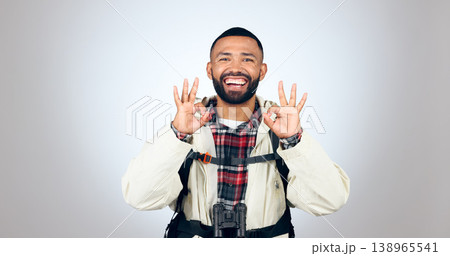 Perfect sign, hiker and portrait of man in a studio with a backpack for hiking adventure. Happy, smile and young male person from Mexico with ok hand gesture for camping isolated by gray background. 138965541