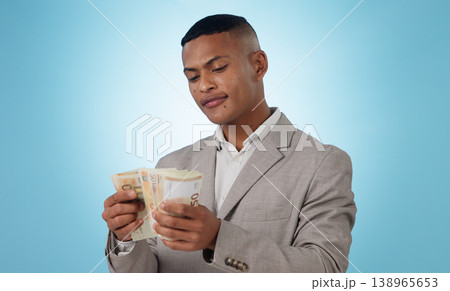 Business man, cash and money for financial investment, budget and trading, profit or counting his savings in studio. Young trader with decision or doubt for income, loan or salary on blue background Business man, cash and money for financial investment, budget and trading, profit or counting his savings in studio. Young trader with decision or doubt for income, loan or salary on blue background 138965653