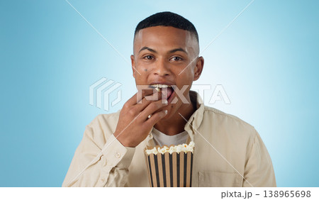 Portrait, happy man and popcorn for cinema in studio on blue background for entertainment mockup. Male model, eating and hungry with delicious, snack and food for watching, television and theatre Portrait, happy man and popcorn for cinema in studio on blue background for entertainment mockup. Male model, eating and hungry with delicious, snack and food for watching, television and theatre 138965698