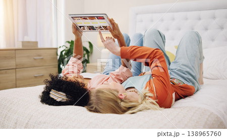Friends relax with tablet to scroll on website for a movie or film choice lying on bed together at home. Technology, decision or people on internet search for ecommerce online shopping on app screen Friends relax with tablet to scroll on website for a movie or film choice lying on bed together at home. Technology, decision or people on internet search for ecommerce online shopping on app screen 138965760