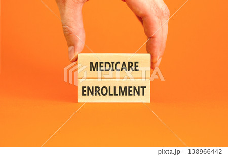 Medicare enrollment words symbol. Concept words Medicare enrollment on beautiful wooden blocks. Beautiful orange background. Doctor hand. Medical and Medicare enrollment words concept. Copy space. Medicare enrollment words symbol. Concept words Medicare enrollment on beautiful wooden blocks. Beautiful orange background. Doctor hand. Medical and Medicare enrollment words concept. Copy space. 138966442