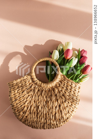 Tulip Bouquet in Straw Handbag. Stylish Spring Floral Composition on Pink Background Tulip Bouquet in Straw Handbag. Stylish Spring Floral Composition on Pink Background 138966652