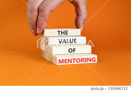 The value of mentoring words symbol. Concept words The value of mentoring on beautiful wooden blocks. Beautiful orange background. Businessman hand. Business the value of mentoring concept. Copy space 138966712