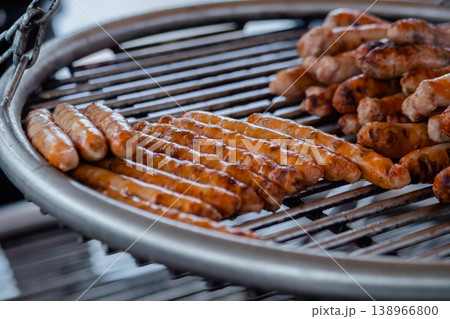 Process of grilling fresh meat sausages on big round hanging grill - close up 138966800