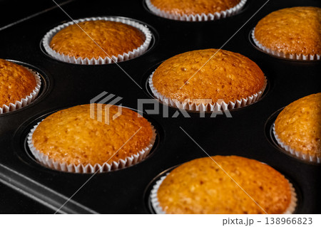Baked cupcakes, muffins in muffin tin in electric oven - close up view Baked cupcakes, muffins in muffin tin in electric oven - close up view 138966823